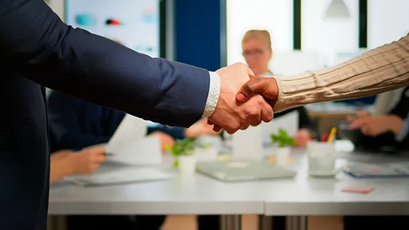 business partners standing in front of conference desk shaking hands 