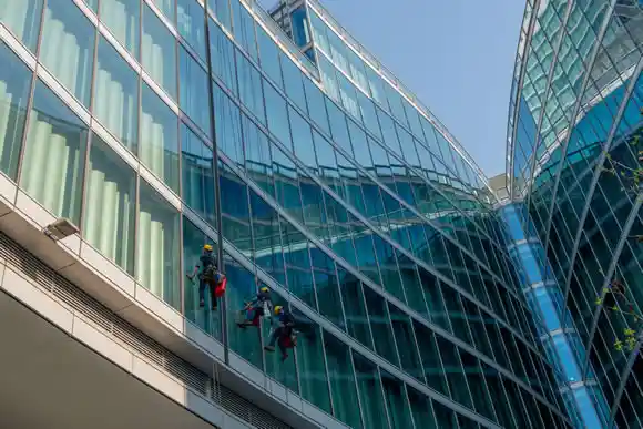 Skilled glass cleaners who lower themselves with slings from above